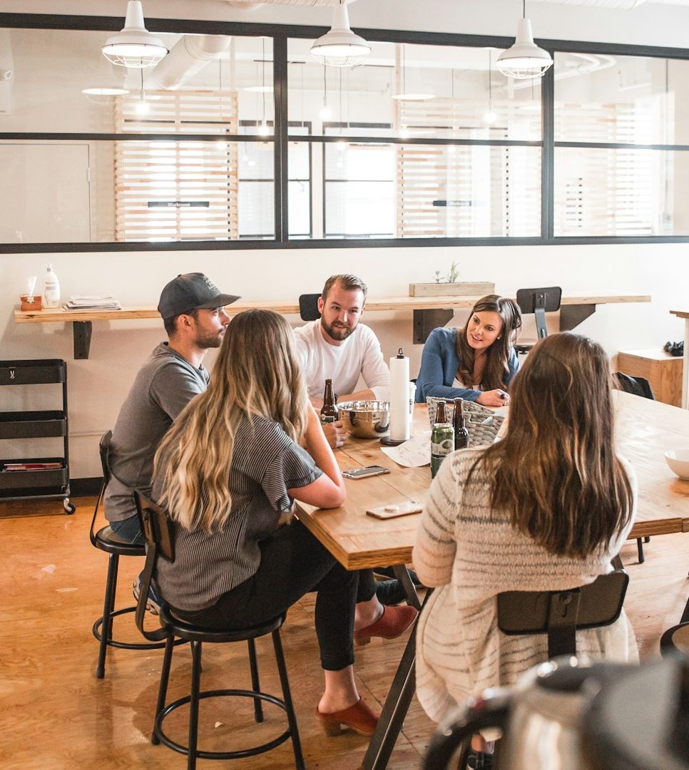 Two men and three women sitting at a table while discussing ideas