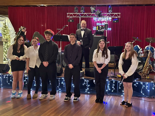 Board President stands behind a group of six young people who volunteered for the Winter Gala event