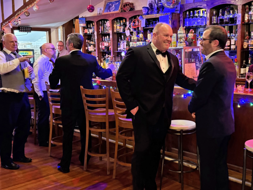 Several men in suits conversing at the bar